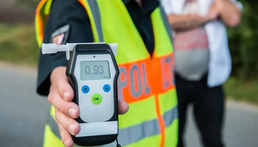 Policjant pokazuje alkomat z wynikiem 0.93 promila. To przypomnienie o **limicie alkoholu w Polsce** i odpowiedzialności za kierownicą.