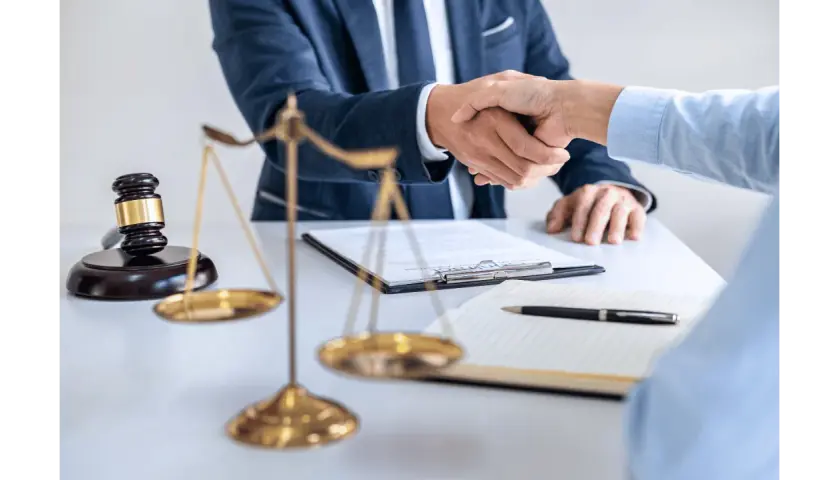 Uścisk dłoni prawników przy biurku z wagą sprawiedliwości i młotkiem. Sprawa 157 kk zakończona sukcesem.