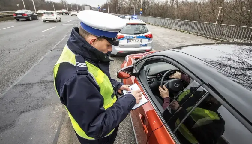 Policjant spisuje mandat. Kierowca zastanawia się, jak się bronić przed art. 97 k.w. w tej sytuacji.