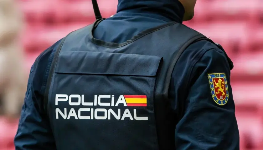 Policjant w kamizelce z napisem "POLICIA NACIONAL" i flagą Hiszpanii. Służba w policji Hiszpanii to odpowiedzialność.