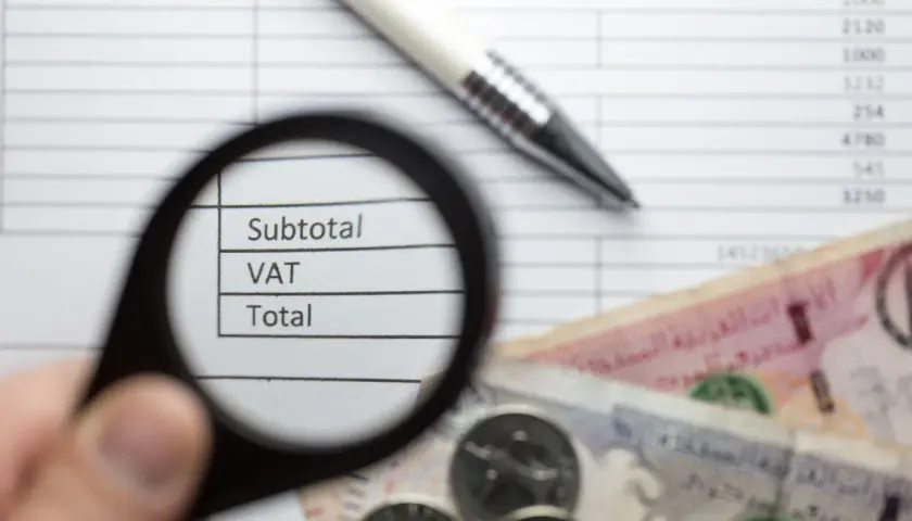 Pod lupą widać napisy "Subtotal", "VAT", "Total" na tle dokumentu z cyframi. Obok leżą banknoty i monety, co sugeruje analizę finansową zgodną z art. 96 ust. 9a pkt 2.