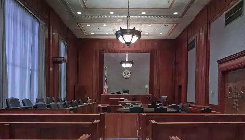 Pusta sala sądowa, gotowa na złożenie **zażalenia**. Drewniane ławy i podwyższenie dla sędziego tworzą uroczystą atmosferę.