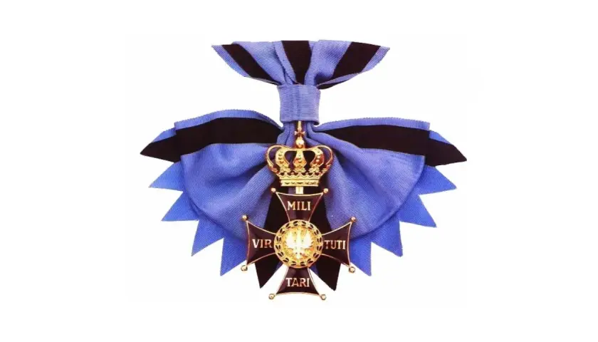 Złoty krzyż z koroną i wstęgą, symbol najwyższego odznaczenia wojskowego Virtuti Militari.