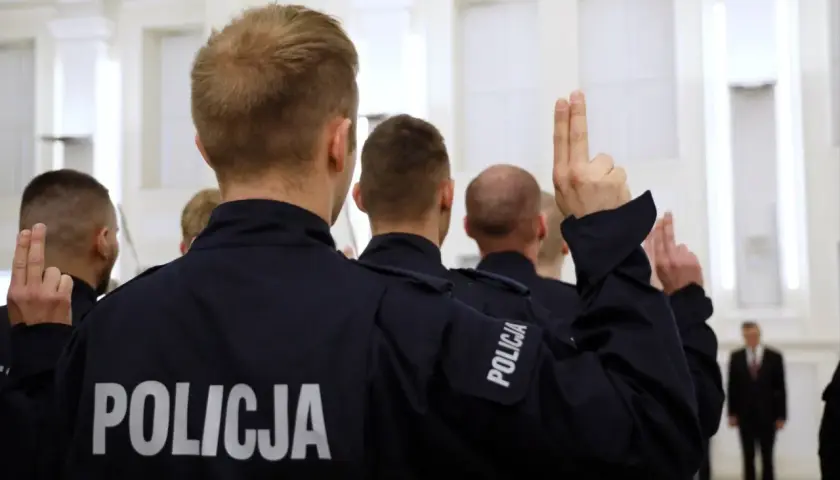 Policjanci w mundurach podnoszą ręce. Zastanawiasz się, ile zarabia pracownik cywilny w policji?