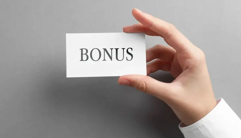 Dłoń trzyma kartkę z napisem "BONUS". To może być dodatek stażowy, który czeka na Ciebie!