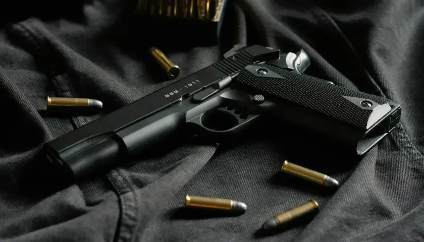 Czarny pistolet GSG-1911 i amunicja na ciemnym tle. Idealny do strzelectwa sportowego.