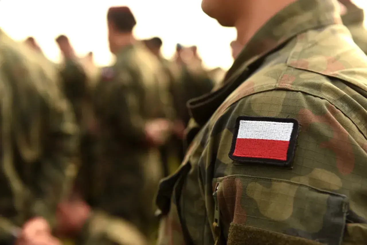 Żołnierz w mundurze polowym z naszywką flagi Polski. Weteran dumny ze swojej służby.