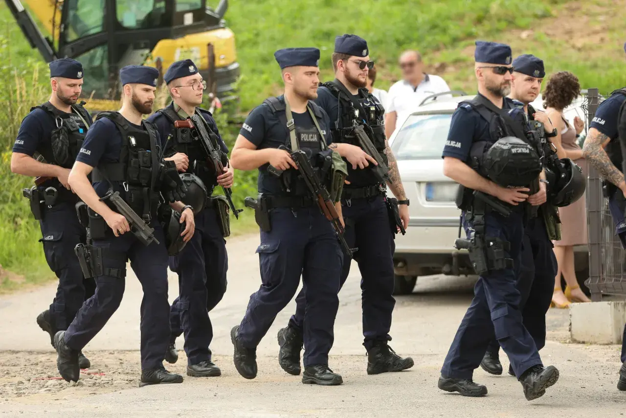 Grupa policjantów w pełnym rynsztunku, z bronią, maszeruje. To szkolenie policyjne, które przygotowuje ich do trudnych zadań.