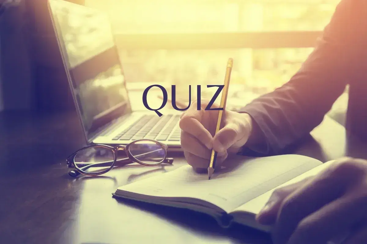 Quiz o prawach pracownika. Osoba pisze w notatniku przy laptopie i okularach.