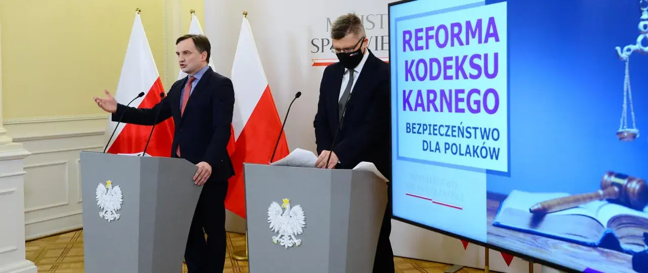 Konferencja prasowa dotycząca reformy kodeksu karnego. Mówcy przy mównicach z godłem Polski, na ekranie hasło "Bezpieczeństwo dla Polaków" i symbole sprawiedliwości.