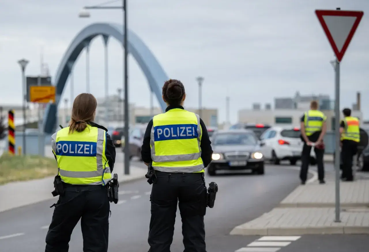 Policjanci w kamizelkach z napisem POLIZEI prowadzą kontrole na granicy niemieckiej. Ruch samochodowy jest spowolniony.