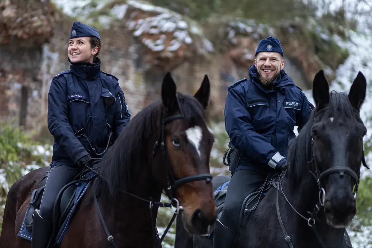 Policjanci na koniach, w tym przełożony, patrolują zimowy teren.