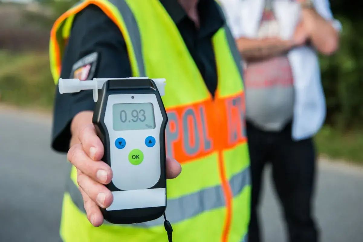 Policjant pokazuje alkomat z wynikiem 0.93 promila. To przypomnienie o **limicie alkoholu w Polsce** i odpowiedzialności za kierownicą.