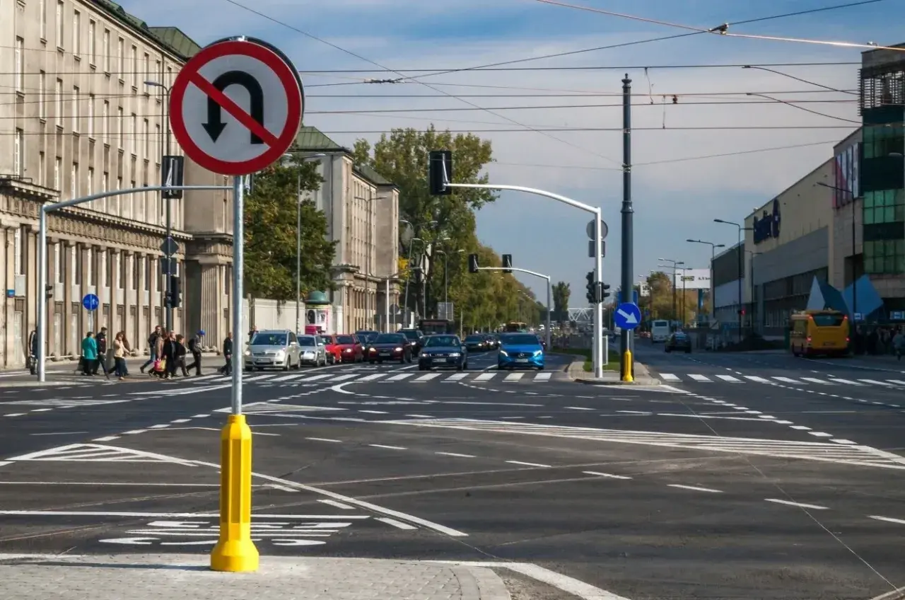 Znak zakazu skrętu w lewo na skrzyżowaniu z ruchem ulicznym i pieszymi.
