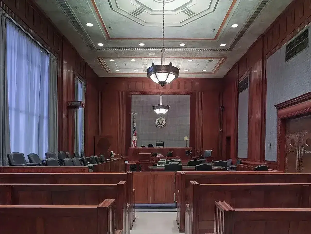 Pusta sala sądowa, gotowa na złożenie **zażalenia**. Drewniane ławy i podwyższenie dla sędziego tworzą uroczystą atmosferę.