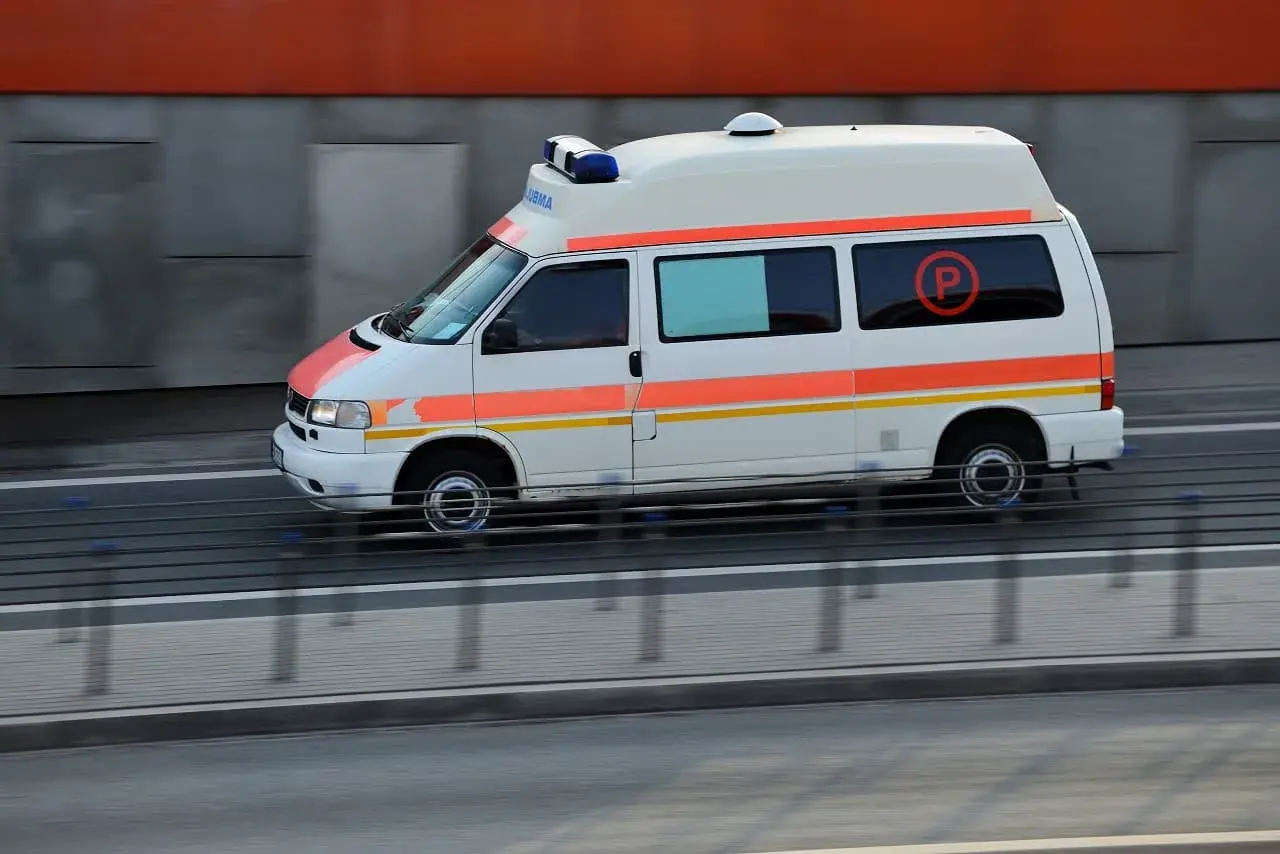 Ambulans z niebieskimi sygnałami świetlnymi, jadący na kursie pojazdy uprzywilejowane.