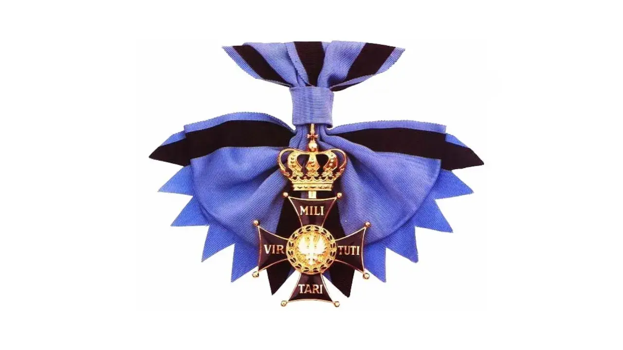 Złoty krzyż z koroną i wstęgą, symbol najwyższego odznaczenia wojskowego Virtuti Militari.