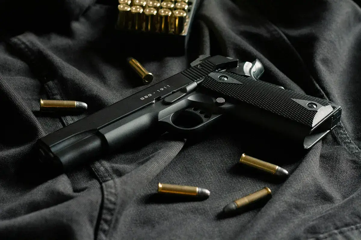 Czarny pistolet GSG-1911 i amunicja na ciemnym tle. Idealny do strzelectwa sportowego.