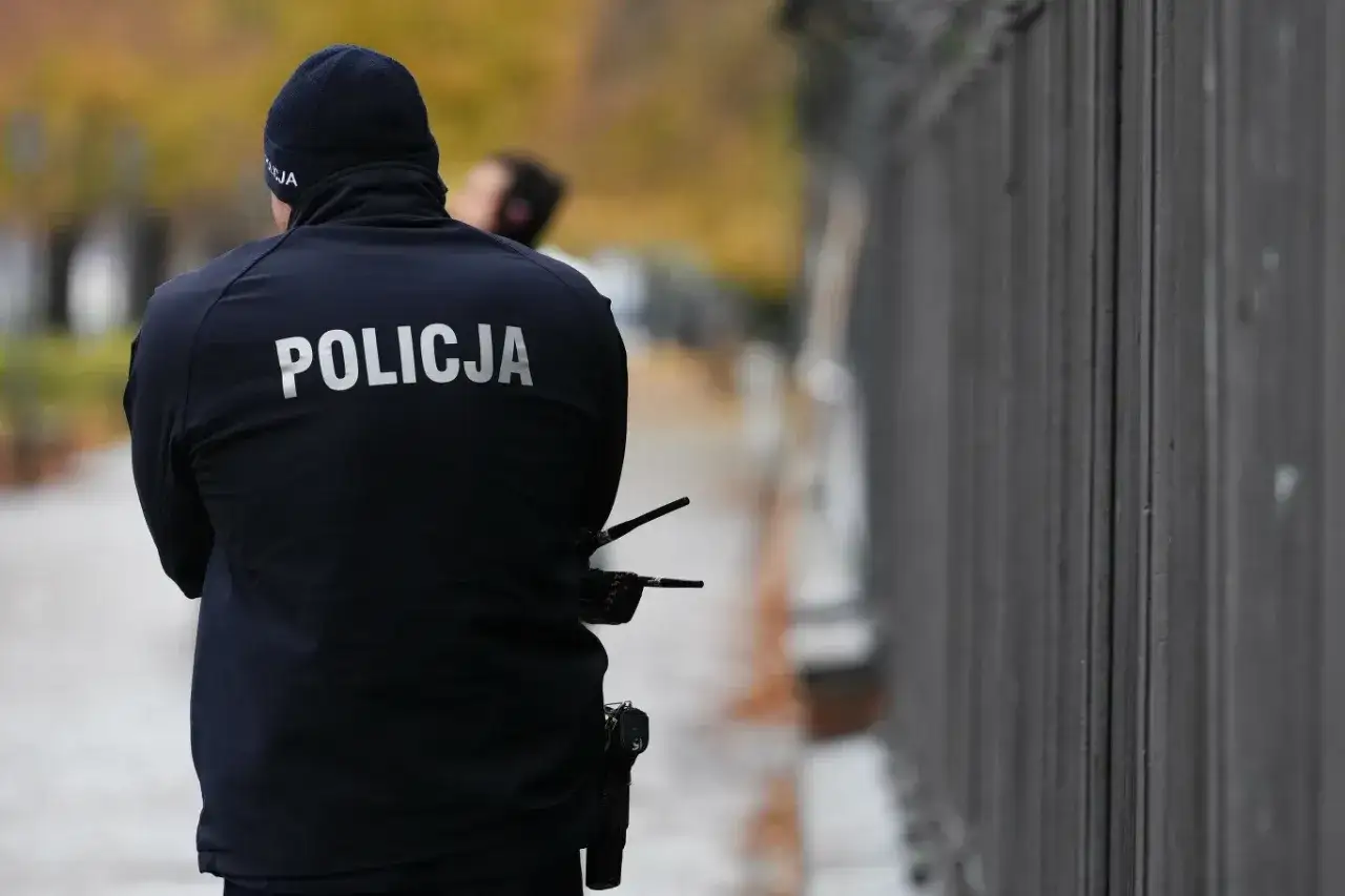 Policjant w czapce i kurtce z napisem 