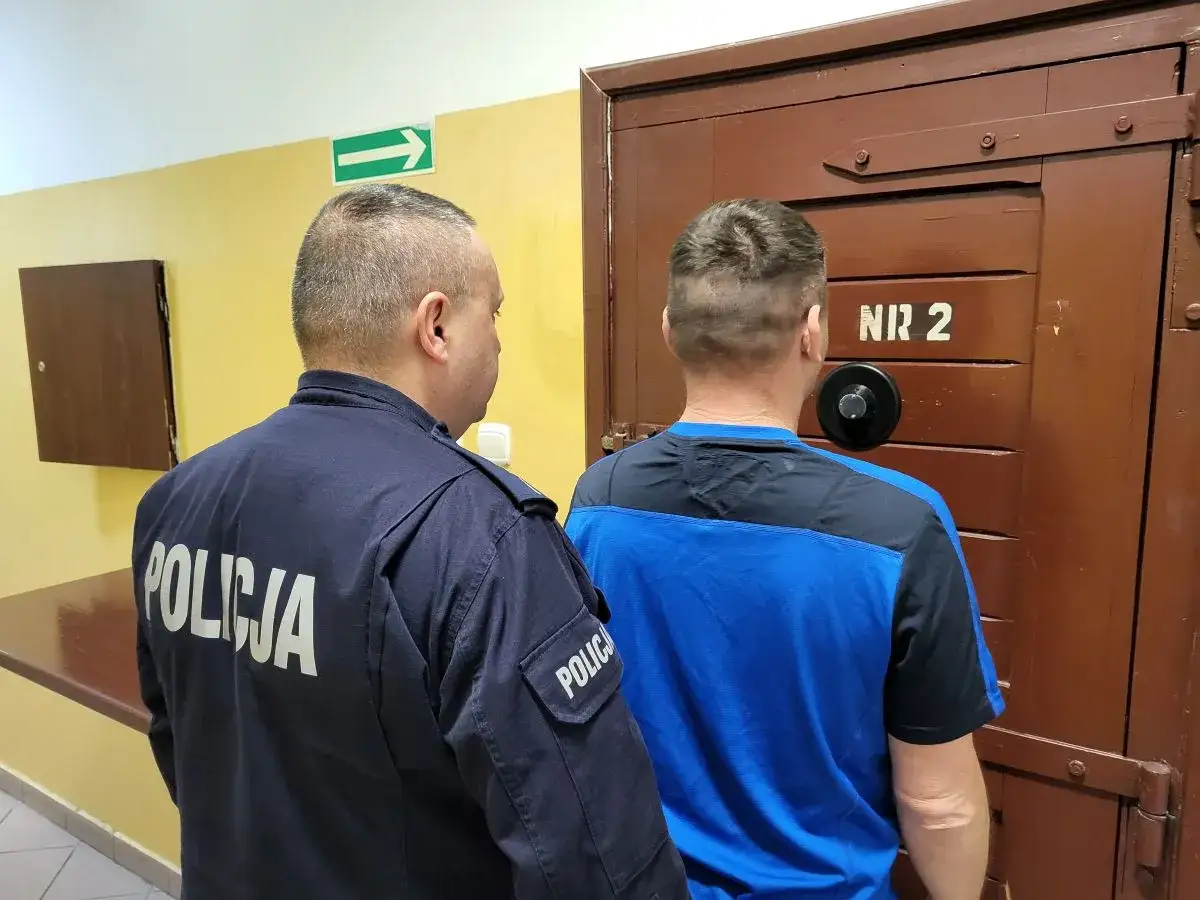 Policjant eskortuje mężczyznę do celi nr 2. Podejrzany o rozbój czeka na dalsze czynności.