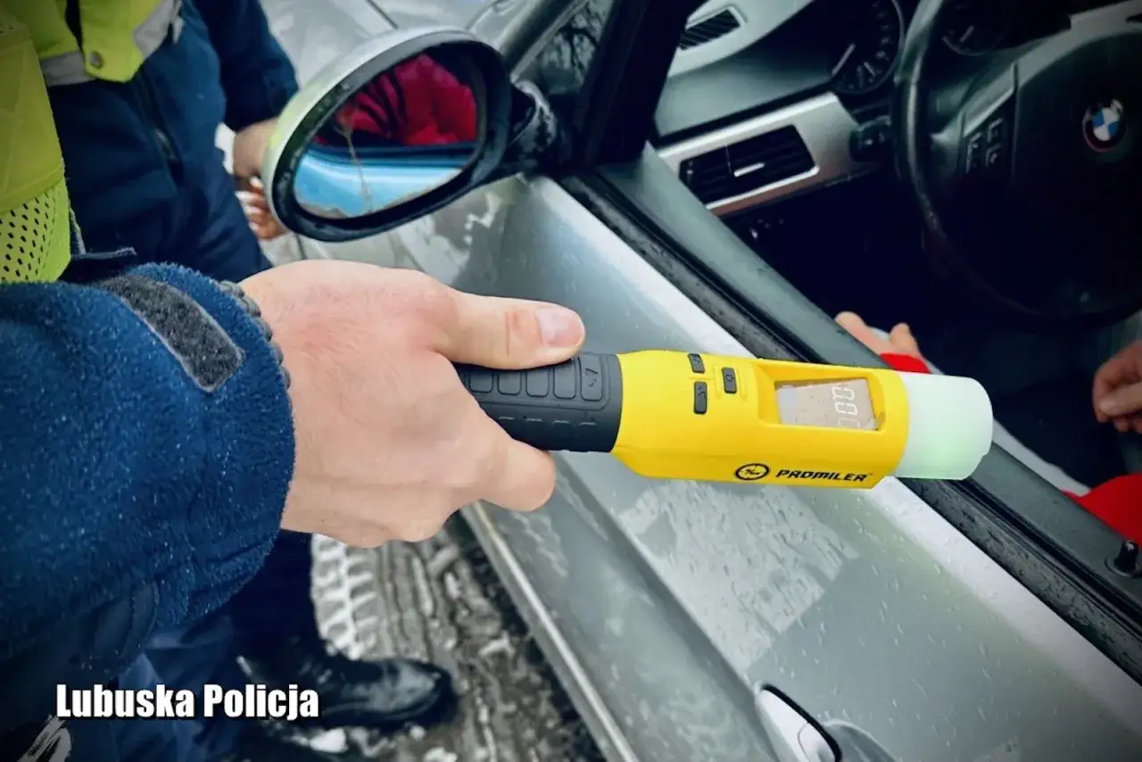 Policjant z Lubuskiej Policji używa alkomatu, by sprawdzić, czy kierowca nie popełnia wykroczenia jazda po alkoholu.