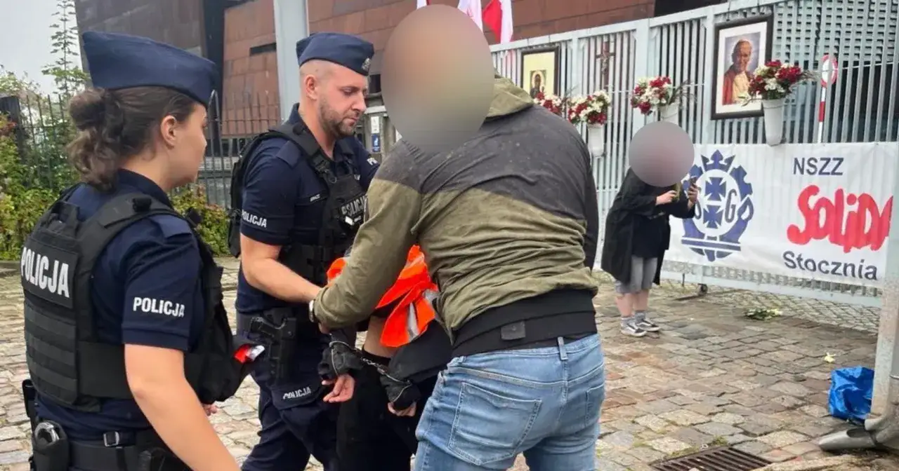 Policja zatrzymuje mężczyznę, który zachowywał się jak chuligan. Jest zakuty w kajdanki.
