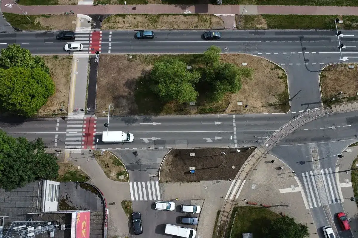 Skrzyżowanie z pasami dla pieszych i rowerzystów. Widoczna sygnalizacja świetlna kierująca ruchem pojazdów.