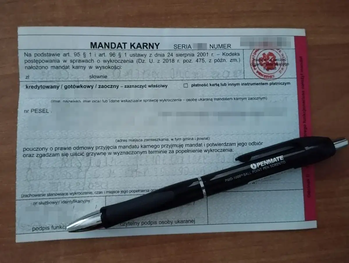 Mandat karny za jazdę rowerem po alkoholu. Długopis PENMATE leży na dokumencie.