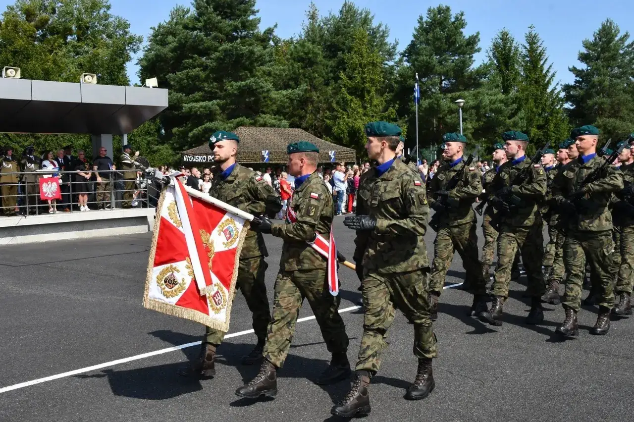 Żołnierze w mundurach maszerują z flagą, składając przysięgę wojskową.