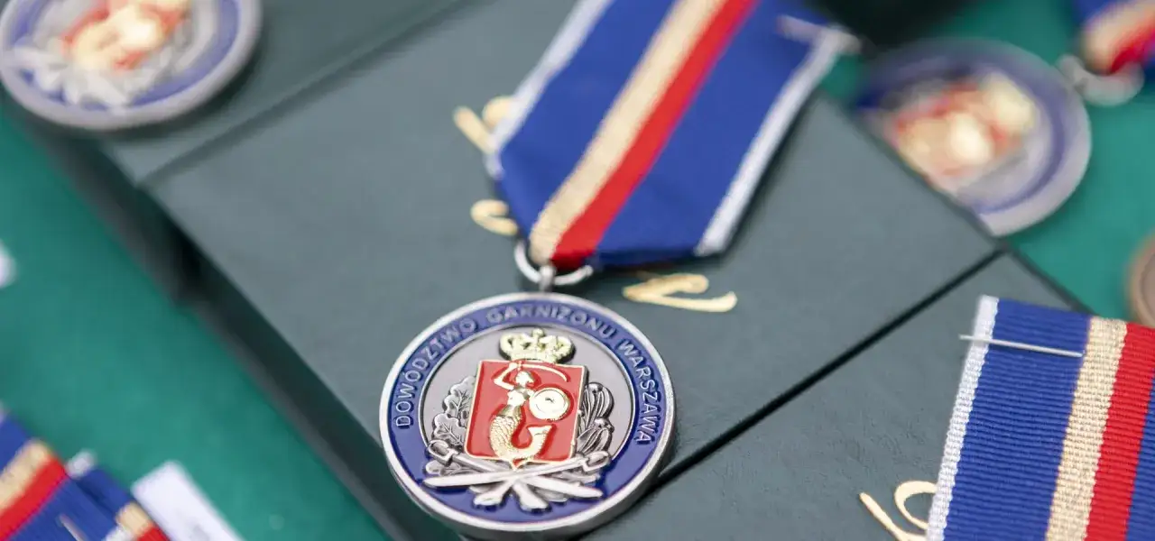 Medal z syrenką i koroną, symbol uznania dla weterana. Wstążka w barwach narodowych.
